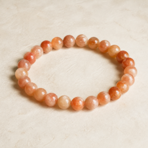 Natural sunstone gemstone bracelet with peach and copper beads on warm ivory paper