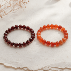 Deep red garnet and warm orange carnelian natural gemstone bracelets arranged for comparison